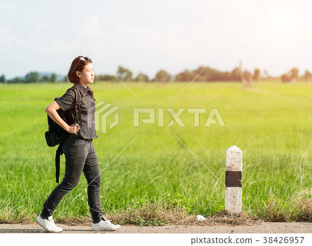 Woman with backpack hitchhiking along a road 38426957