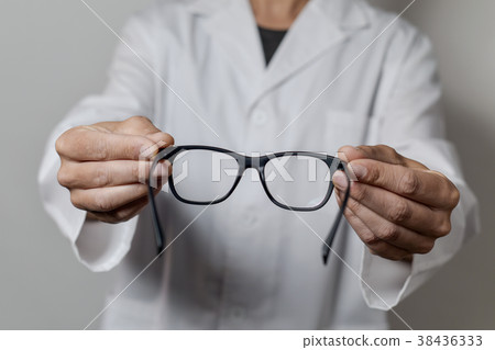 optician man bringing a pair of eyeglasses 38436333