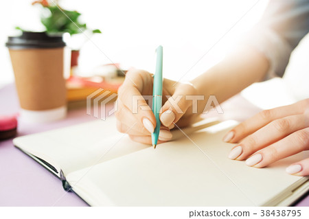 The female hands holding pen. The trendy pink desk The female hands holding pen. The trendy pink desk 38438795