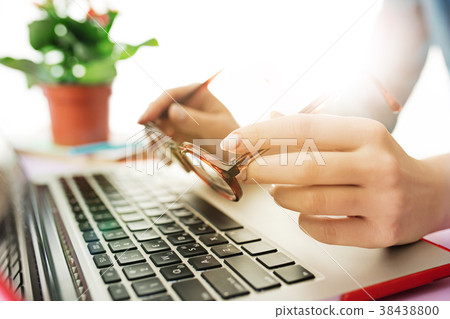Woman working on computer in office and holding Woman working on computer in office and holding 38438800