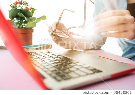 Woman working on computer in office and holding Woman working on computer in office and holding 38438801