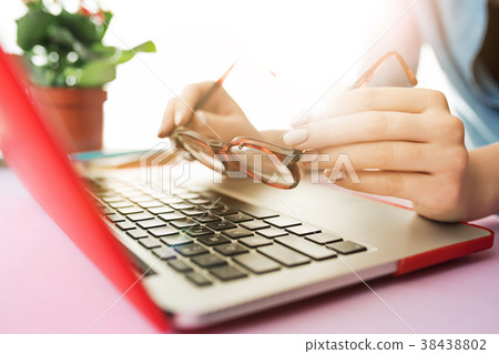 Woman working on computer in office and holding Woman working on computer in office and holding 38438802