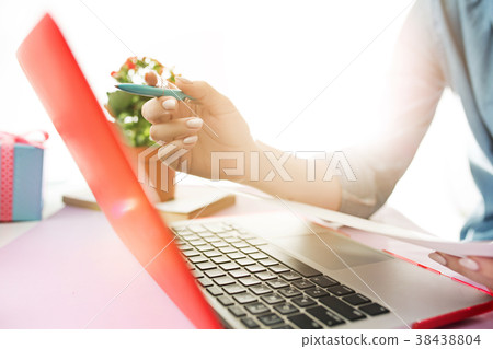 Woman working on computer in office and holding Woman working on computer in office and holding 38438804