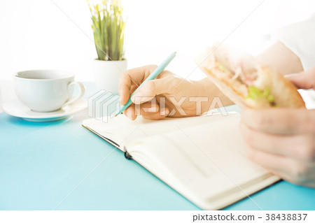 The male hands holding pen and sandwich. The The male hands holding pen and sandwich. The 38438837