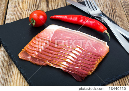 Slices of smoked bacon on black stone Slices of smoked bacon on black stone 38440330