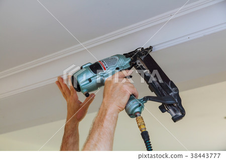 Carpenter brad using nail gun to Crown Moulding 38443777