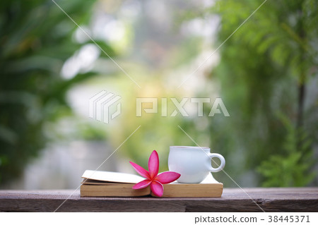 White cup with flower and notebook on wooden table White cup with flower and notebook on wooden table 38445371