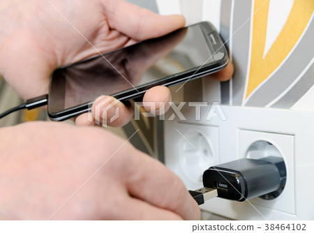 A man is charging the smartphon. 38464102
