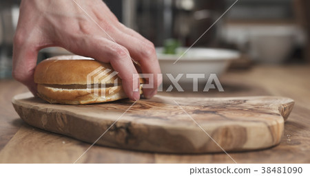 Man hands making bagel sandwich on wood board Man hands making bagel sandwich on wood board 38481090