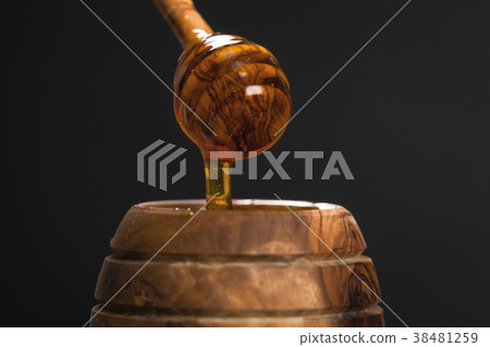honey drips from dipper over dark background honey drips from dipper over dark background 38481259