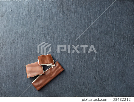 A few pieces of milk chocolate on dark background 38482212