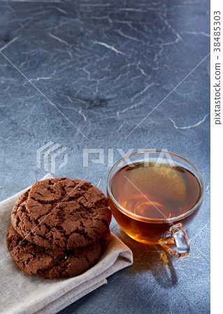 A glass cup of black tea with cookies on a dark A glass cup of black tea with cookies on a dark 38485303