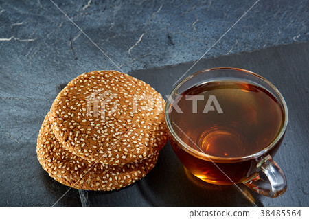 A glass cup of black tea with cookies on a dark A glass cup of black tea with cookies on a dark 38485564