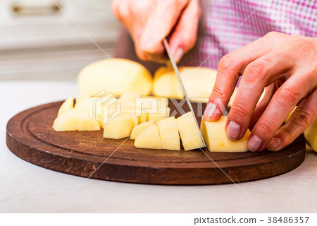 Female hands cut potatoes on wooden board 38486357