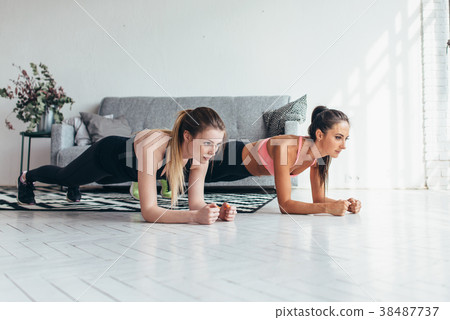 Two fit women doing plank exercise on floor at 38487737
