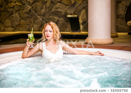 woman in white swimsuit sits in jacuzzi in spa woman in white swimsuit sits in jacuzzi in spa 38489798