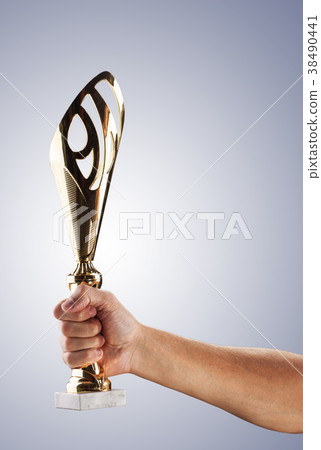 Man's hand in a blue fire is holding gold cup Man's hand in a blue fire is holding gold cup 38490441