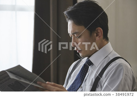 Stylish businessman reading English newspaper Stylish businessman reading English newspaper 38491972