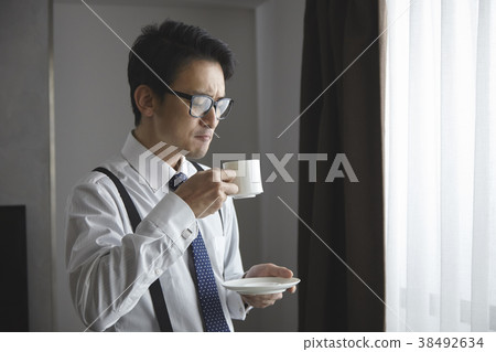 時髦的商人飲用的咖啡在客廳 時髦的商人飲用的咖啡在客廳 38492634