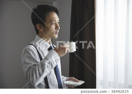 時髦的商人飲用的咖啡在客廳 時髦的商人飲用的咖啡在客廳 38492635