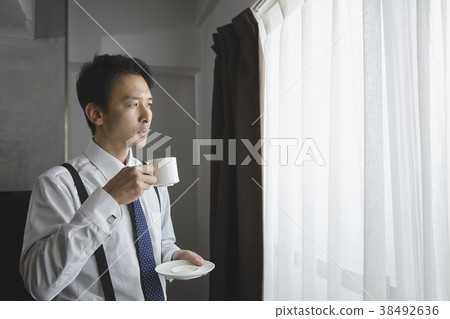 時髦的商人飲用的咖啡在客廳 時髦的商人飲用的咖啡在客廳 38492636