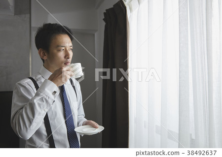 時髦的商人飲用的咖啡在客廳 時髦的商人飲用的咖啡在客廳 38492637