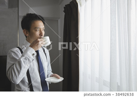 時髦的商人飲用的咖啡在客廳 時髦的商人飲用的咖啡在客廳 38492638