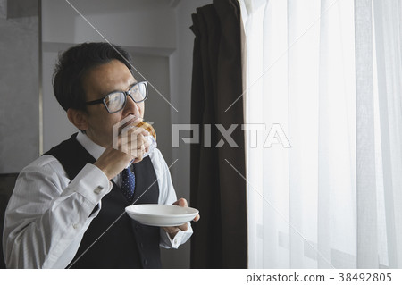 Stylish businessman eating bread in the living room Stylish businessman eating bread in the living room 38492805