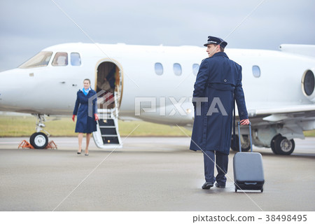 Beaming pilot walking to aircraft 38498495