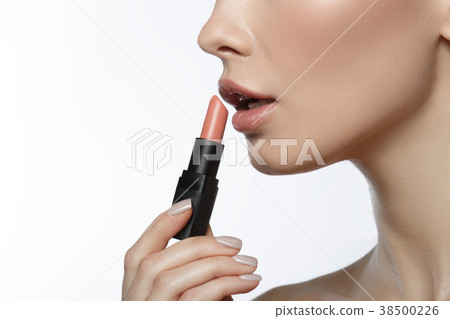 Young woman putting lipstick on mouth Young woman putting lipstick on mouth 38500226