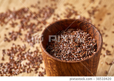 A wooden bowl with linseeds on a rustic background 38510420
