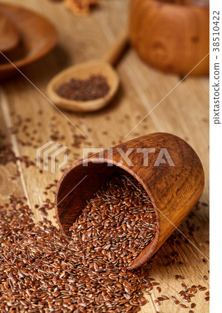 An overturned wooden bowl with linseeds on a An overturned wooden bowl with linseeds on a 38510422