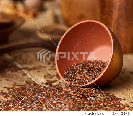 An overturned ceramic bowl with linseeds on a An overturned ceramic bowl with linseeds on a 38510426