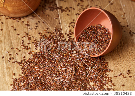 An overturned ceramic bowl with linseeds on a An overturned ceramic bowl with linseeds on a 38510428