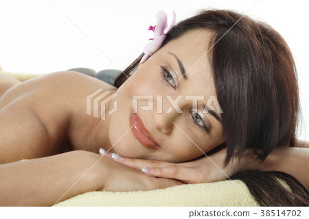 Young woman relaxing with flower and hot stones Young woman relaxing with flower and hot stones 38514702