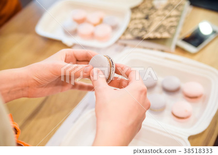 Female hands put together French macaron Female hands put together French macaron 38518333
