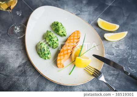 Dish with grilled salmon with lemon slices 38519301