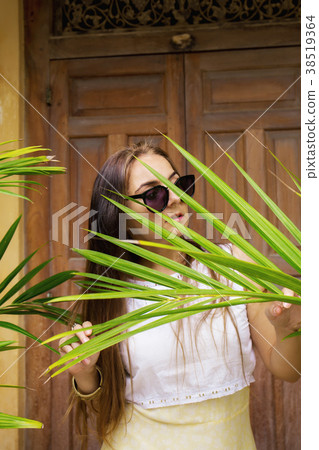 woman hides behind a palm leaf woman hides behind a palm leaf 38519364