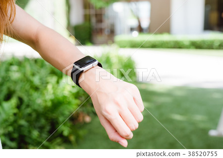 woman looking on her smartwatch in the green. 38520755