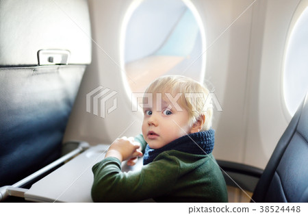 Afraid little boy sitting by aircraft window during the flight 38524448