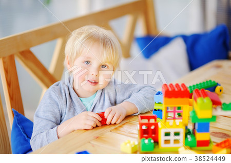 Little boy playing with colorful plastic blocks at kindergarten or at home Little boy playing with colorful plastic blocks at kindergarten or at home 38524449