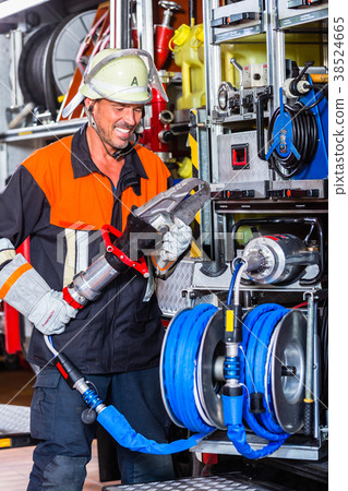 Fire fighter checking hydraulic cutter at fire 38524665