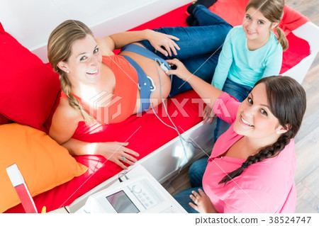 Young girl watching midwife attaching CTG to 38524747