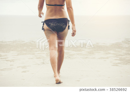 Woman brown bikini walking on white sand beach 38526692