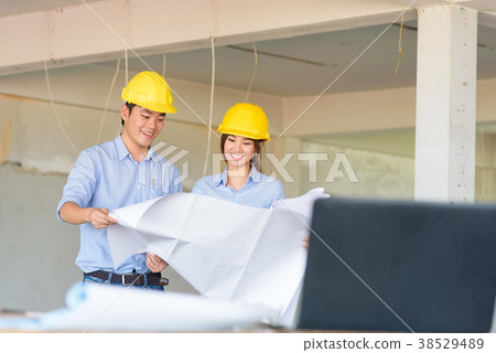 Asian smart engineer holding blueprint and explain details for h Asian smart engineer holding blueprint and explain details for h 38529489