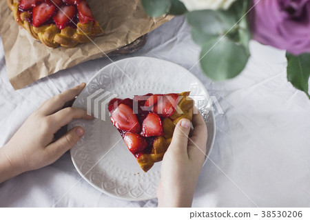 Home made strawberry pie in child's hands on table Home made strawberry pie in child's hands on table 38530206