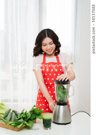 Young asian woman making green detox smoothie Young asian woman making green detox smoothie 38537088