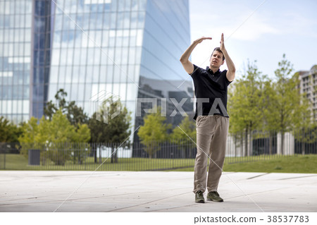 Man Making Hand Gesture in Front of Glass Building 38537783