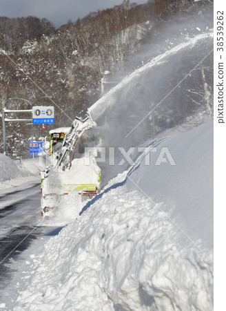 Taking a picture of snowplow landscape of Hokkaido Development Bureau doing snow removal on a national road in the morning with heavy snowfall 38539262