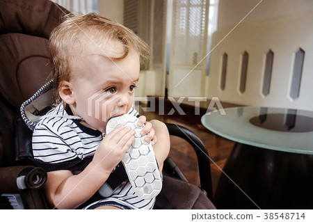 Baby biting shoe sitting in armchair Baby biting shoe sitting in armchair 38548714